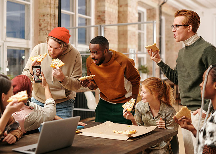Group of coworkers enjoying pizza together in a casual office setting illustrating food thieves at work lesson.