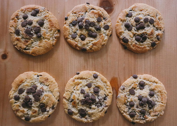 Six chocolate chip cookies arranged on a wooden table, illustrating food thieves at work lesson concept.