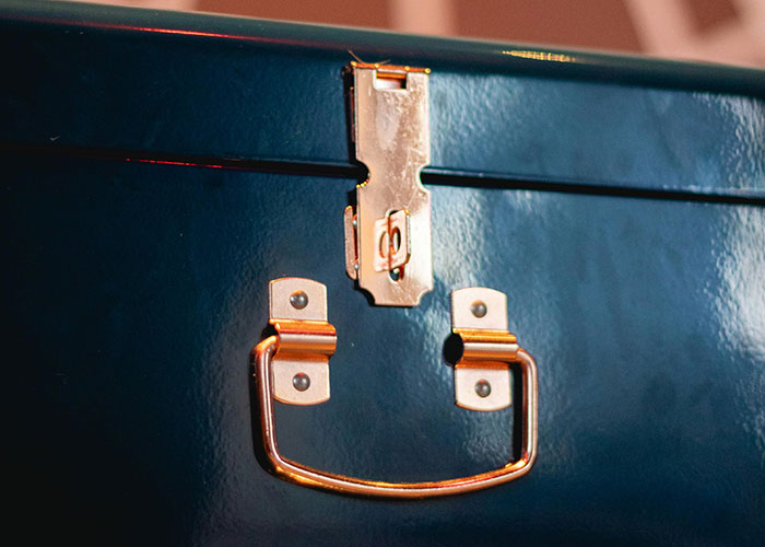 Close-up of a locked blue lunchbox with golden handle, symbolizing preventing food thieves at work.