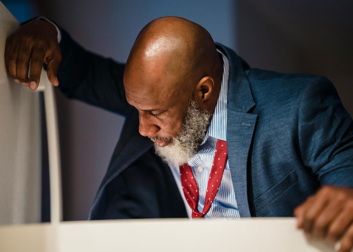 Man in a suit with a red tie looking down, symbolizing lessons taught to food thieves at work.