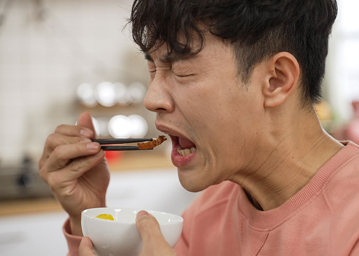 Man eating food with chopsticks, showing strong reaction, illustrating food thieves at work lesson concept.