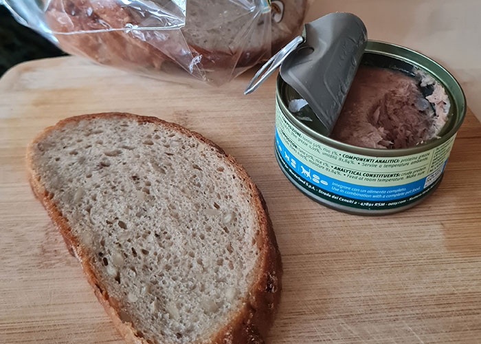 Open can of food with slice of bread on wooden cutting board, illustrating food thieves at work lesson.