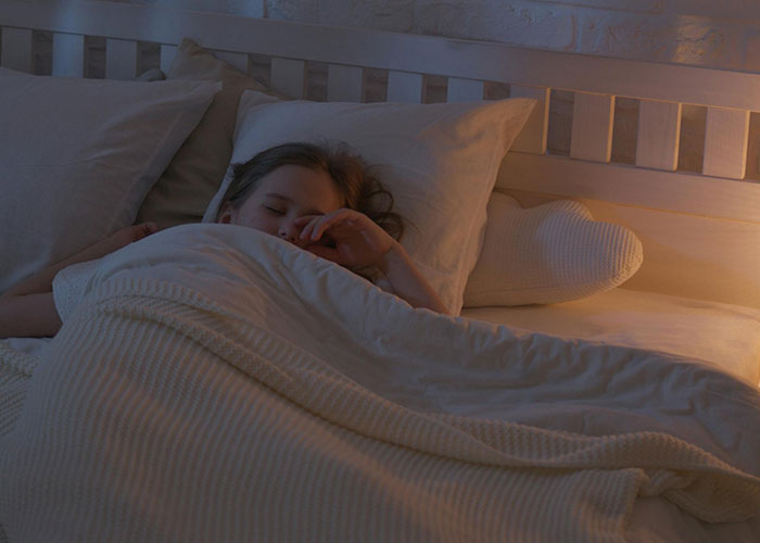Girl sleeping peacefully in bed covered with a white blanket, illustrating common things people believed were normal.