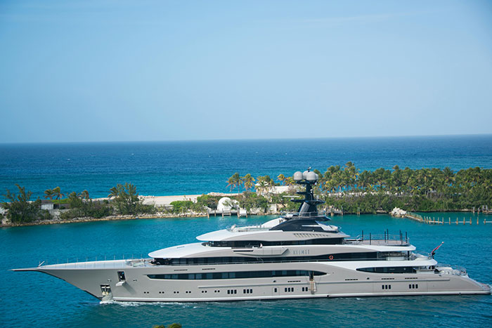 Luxury yacht anchored near tropical island, illustrating lifestyle of ultra rich individuals with insider information.