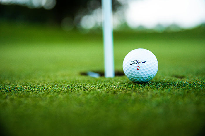Close-up of a golf ball near the hole on a green, illustrating leisure activities ultra rich individuals can afford.