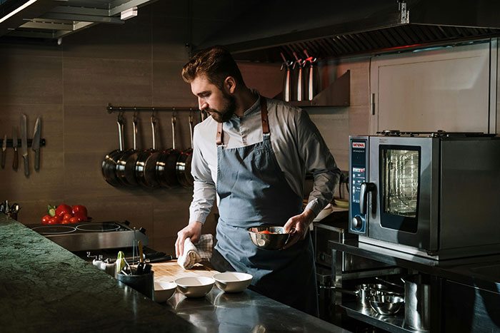 Chef in a luxury kitchen preparing a meal, illustrating things ultra rich individuals can afford to do with insider information.
