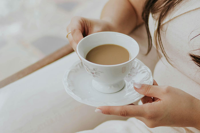 Woman holding a cup of coffee, illustrating a simple luxury that ultra rich individuals can afford to enjoy.