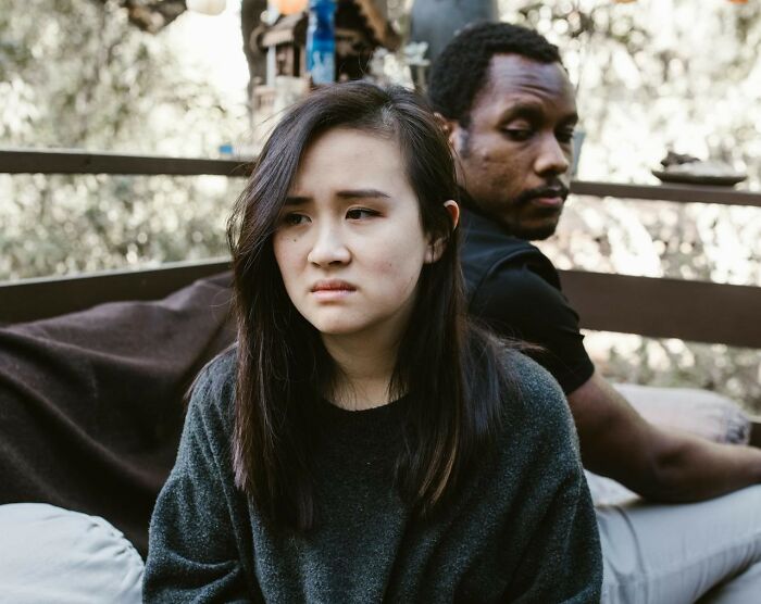 Young woman and man sitting apart, showing frustration and distance, illustrating challenges women want men to understand.