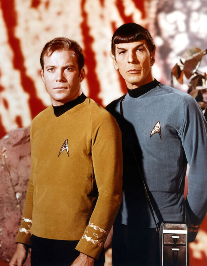 Two iconic duos in classic sci-fi uniforms facing forward, set against a blurred background.