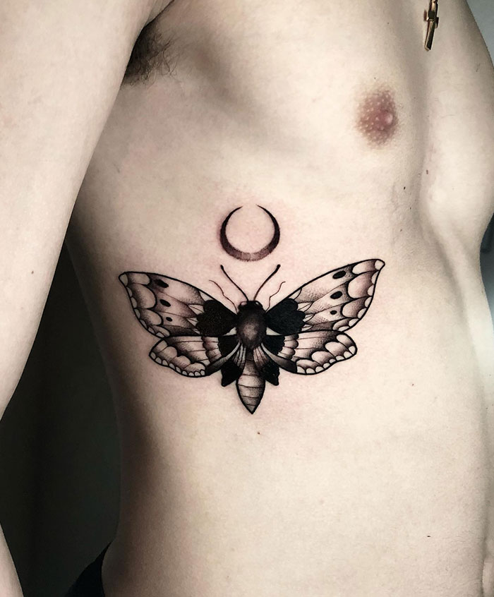  Elegant tattoo ideas for men featuring a black ink moth with detailed wings beneath a crescent moon symbol, combining nature and celestial elements for a mystical design.