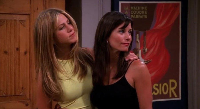 Two women standing together, highlighting an iconic duo, with one in a yellow dress and the other in a black top.