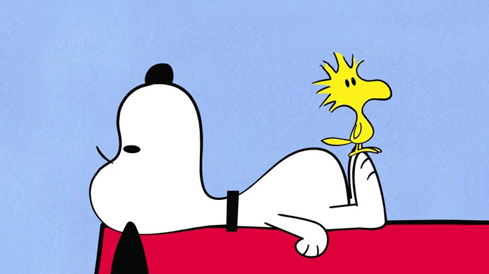 Iconic duos: cartoon dog lounging on red roof with yellow bird perched on back.