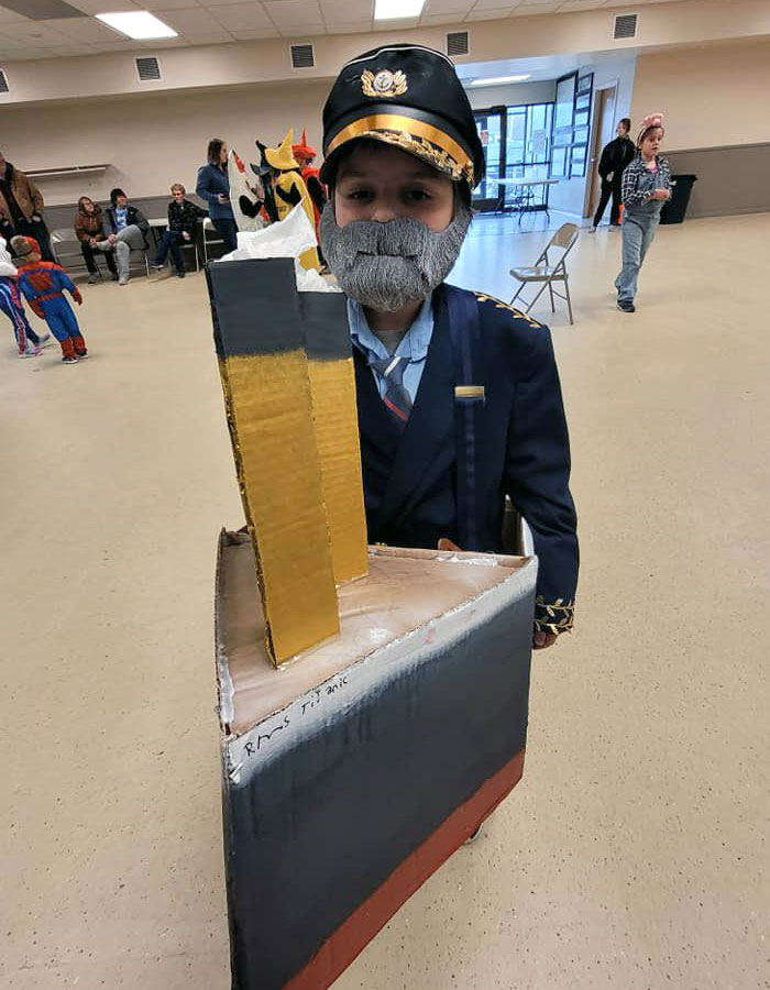 Child dressed as ship captain with cardboard ship costume at kids' Halloween costume event with creative ideas.