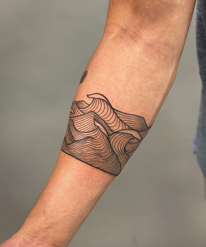 Modern tattoo ideas for men featuring a forearm band design with intricate wave patterns made of thin, flowing lines, creating a sleek and dynamic minimalist style.
