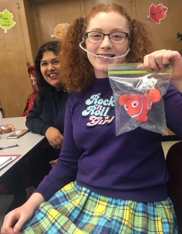 Girl in colorful Halloween costume holding a plastic bag with a clownfish toy, showcasing creative kids' Halloween costume ideas.