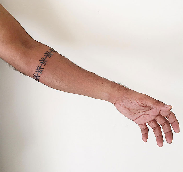 Geometric tattoo ideas for men featuring a forearm band with symmetrical, interlocking lines creating a repeating pattern for a sleek and modern minimalist look.