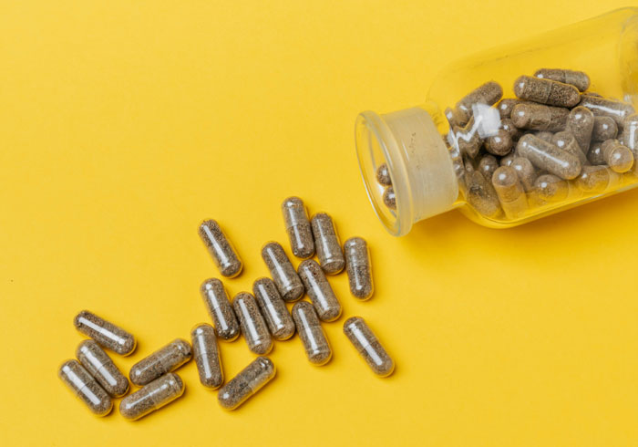Brown capsules spilling out of a clear bottle on a yellow background, related to stories about Kevin and village deprivation.