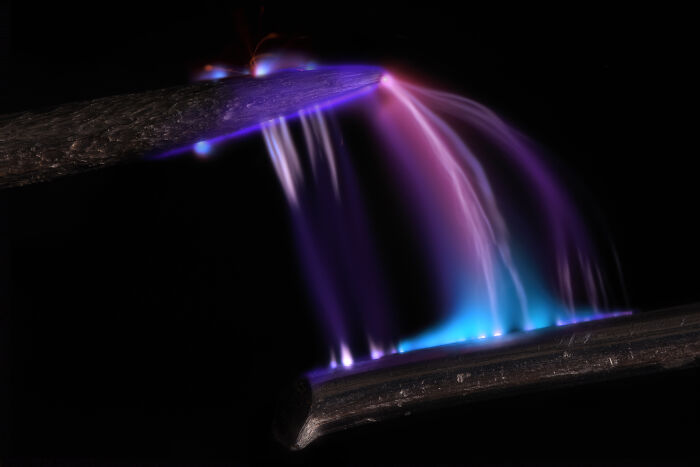 Microscopic image from the 2024 Nikon Small World contest showing colorful light patterns on metallic surfaces.