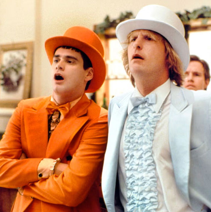 Two men in vibrant suits, one in orange and one in light blue, representing iconic duos.