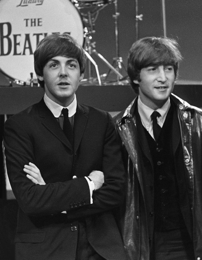 Two members of The Beatles, one in a suit and the other in a leather jacket, representing iconic duos.
