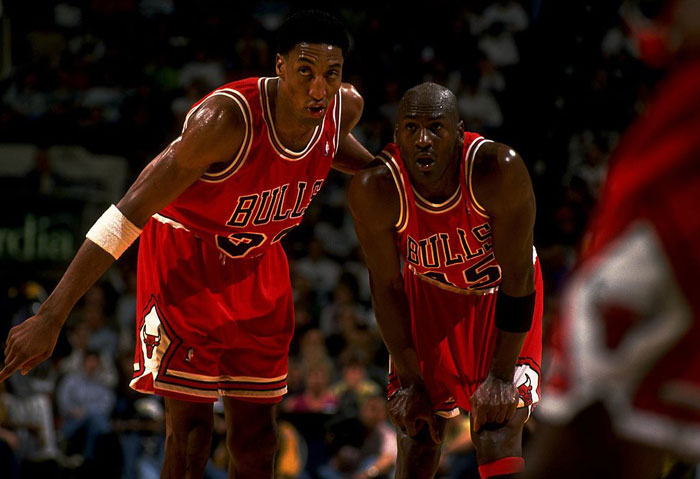 Two basketball players in Chicago Bulls uniforms during a game, representing iconic duos in sports history.