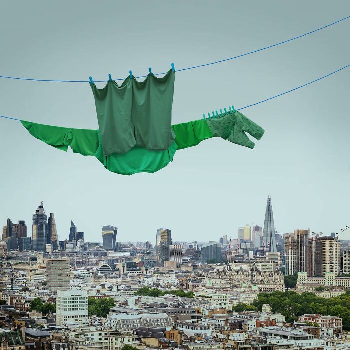 Playful animal made from laundry hanging on clothesline above cityscape, captured in picturesque landscape photography.