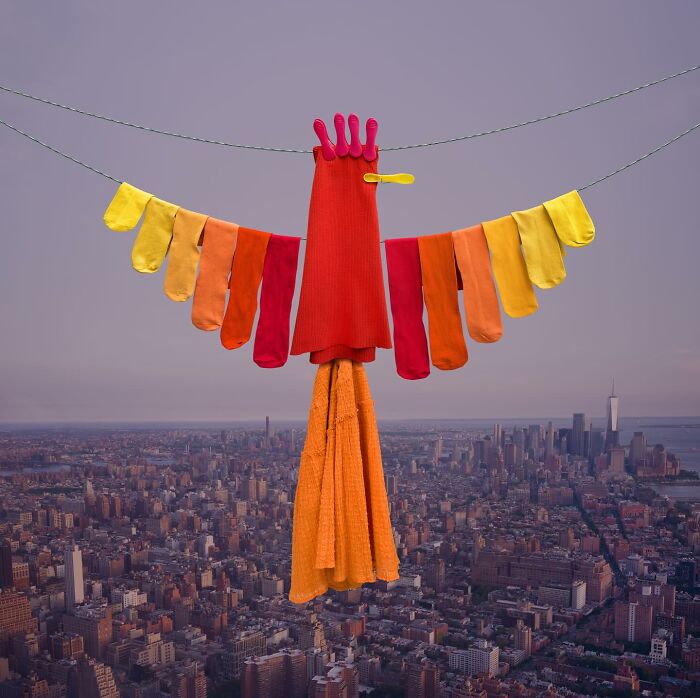 Playful animal made from colorful laundry hanging on a line above a cityscape in picturesque landscapes.
