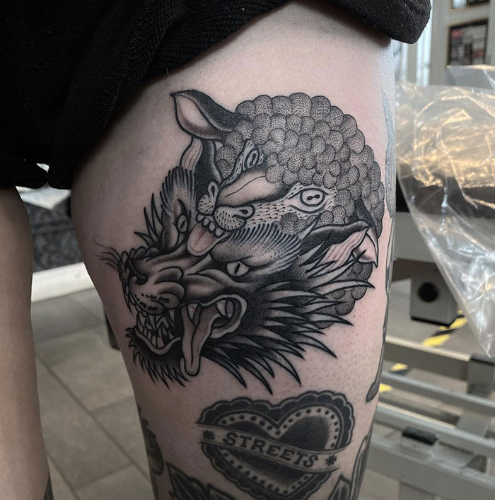  A thigh tattoo of a wolf and sheep merged together, symbolizing duality and inner conflict, offering unique tattoo ideas for men with intricate details and shading.