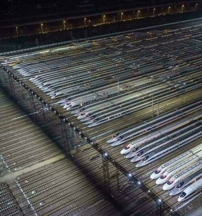 A vast array of sleek bullet trains lined up at night, illustrating scale that can trigger megalophobia fear.