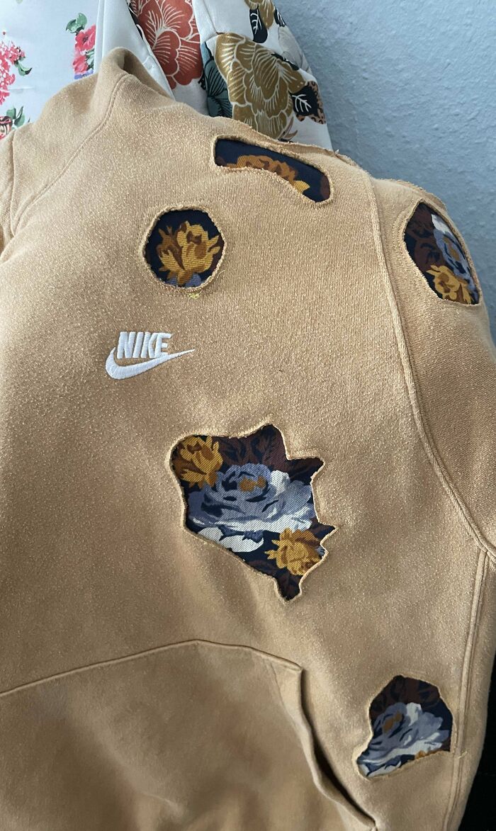 Beige Nike sweatshirt with visible mended holes patched with floral fabric showcasing creative repairs.