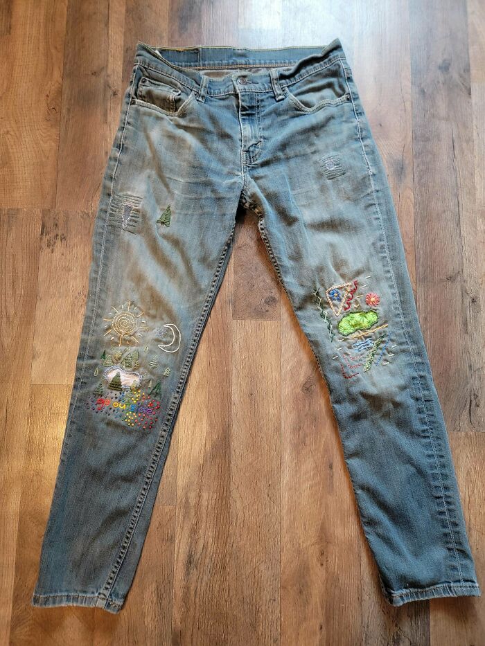 Faded jeans with visible mended patches featuring colorful embroidery, showcasing creative repairs that made them cooler.