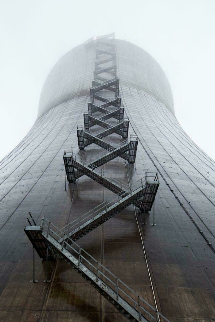 Tall industrial building with zigzagging metal staircase, emitting an evil aura like a supervillain headquarters in foggy weather.