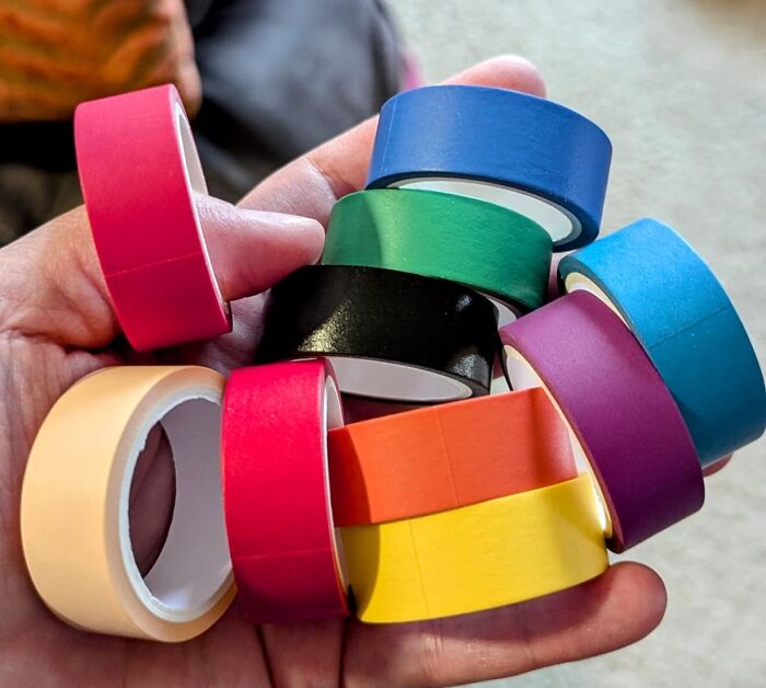Hand holding colorful tape rolls for DIY home projects.