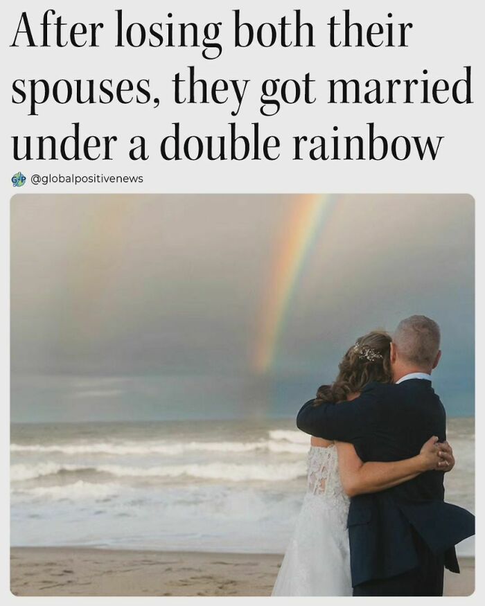 Couple embraces on a beach under a double rainbow, symbolizing restored faith in humanity through love and new beginnings.
