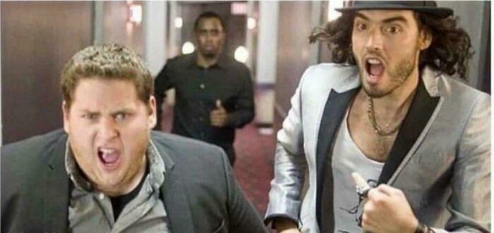 Two men in a hallway, energetically expressing surprise, fitting the theme "Aged Like Wine," embodying predictions coming true.