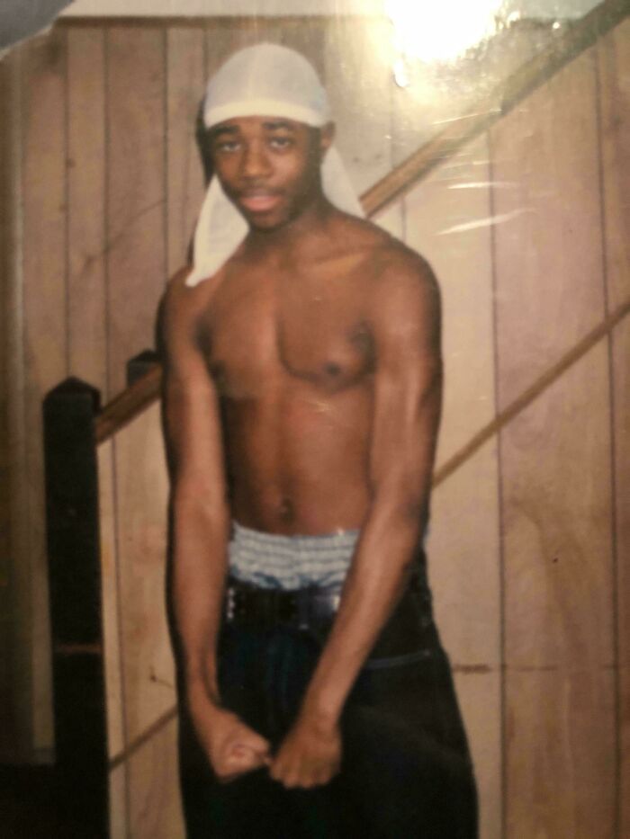 Young man in "blunder years" posing shirtless indoors, wearing a durag and jeans.