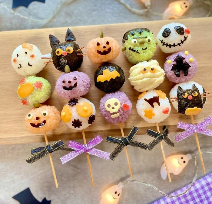 Halloween snacks displayed on skewers decorated as pumpkins, bats, ghosts, and other spooky characters for festive treats.