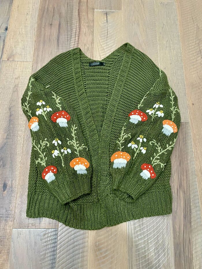 Green knitted sweater with mushroom and flower embroidery, found while thrifting for unique fashion treasures.