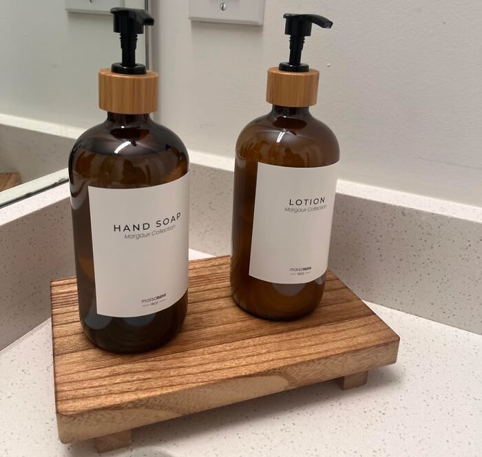 Brown glass hand soap and lotion bottles with wooden pump tops on a wooden tray, showcasing expensive taste on a humble budget.