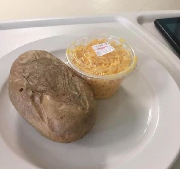 Hospital food example showing a small portion of grated cheese in a plastic cup with a loaf of bread on a white tray.
