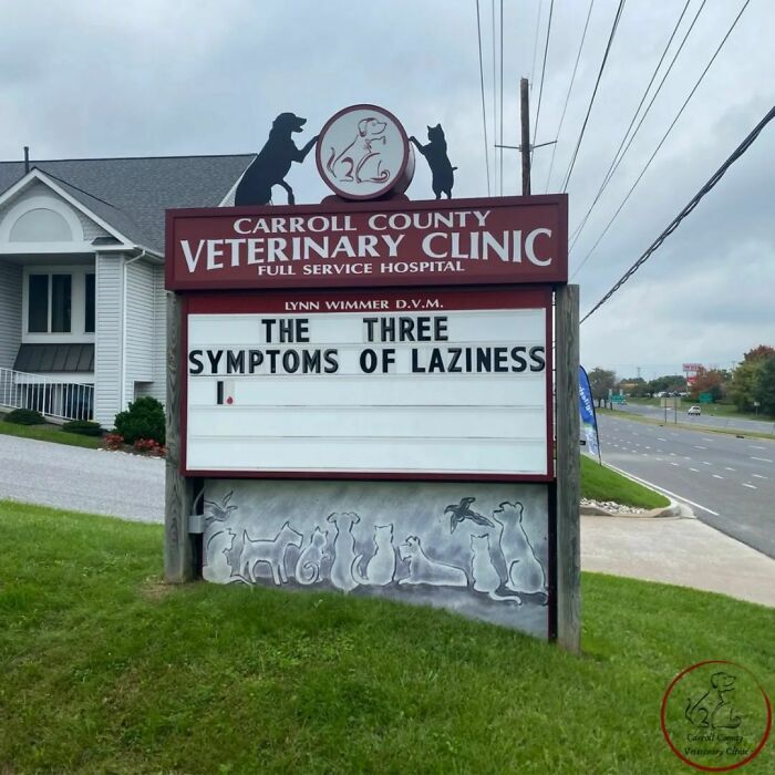 Veterinary clinic sign with a humorous joke about laziness symptoms.
