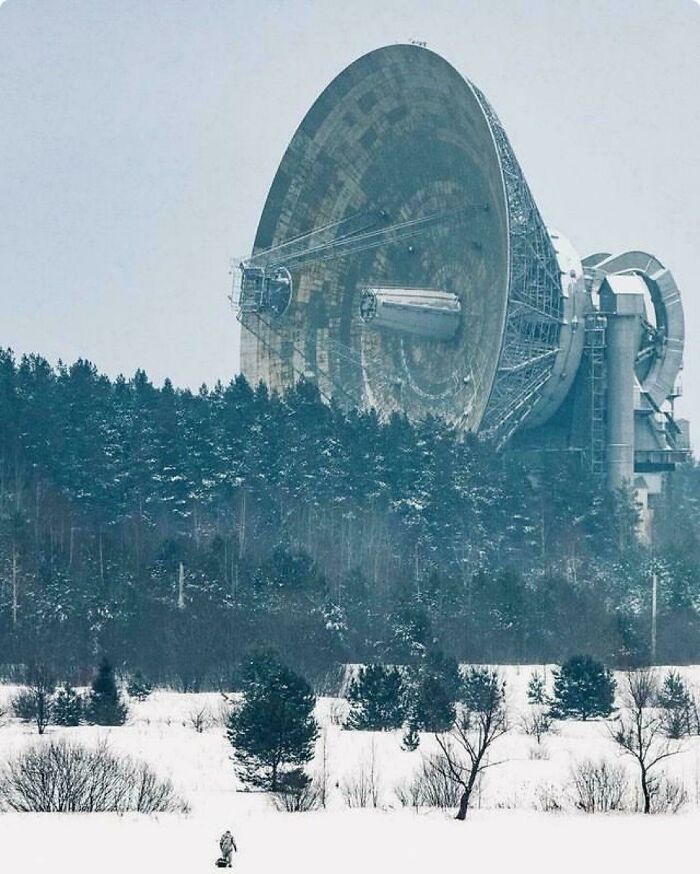 Massive satellite dish tower among snow-covered trees, a building with an evil aura like a supervillain headquarters.