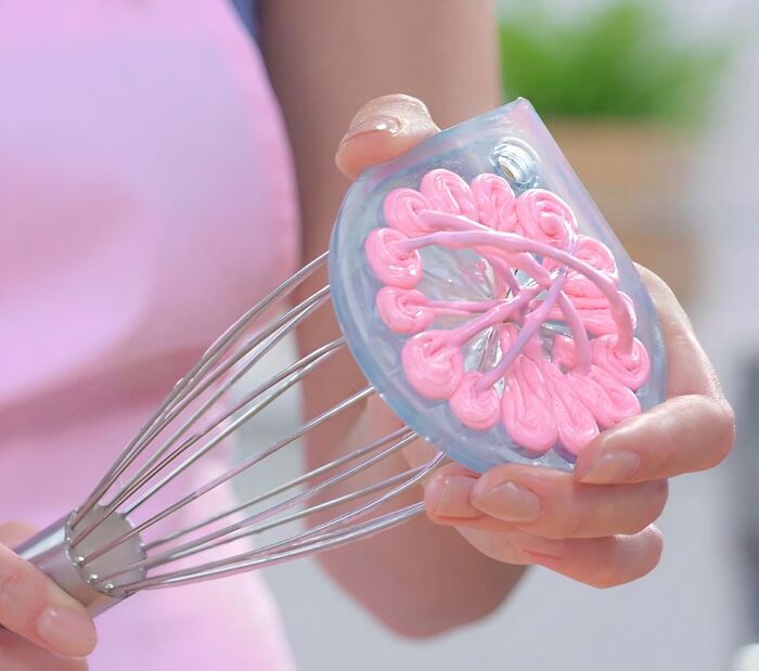 Hand holding a unique kitchen tool with pink silicone detail on a metal whisk, showcasing crazy kitchen logic innovation.