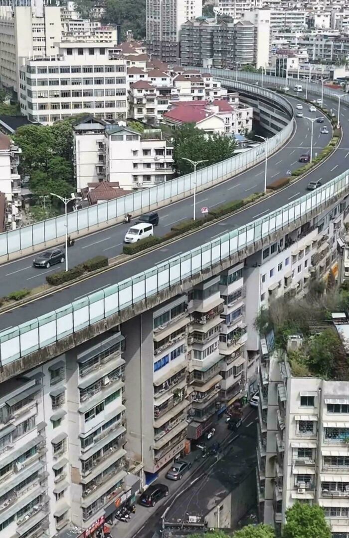 Urban landscape with a highway passing through residential buildings, highlighting urban hell aspects.