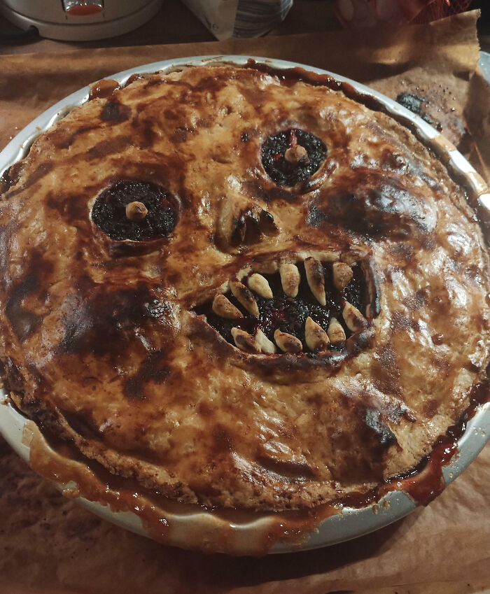 Halloween snack pie designed with a scary face featuring almond teeth and dark fruit filling in a baked crust.