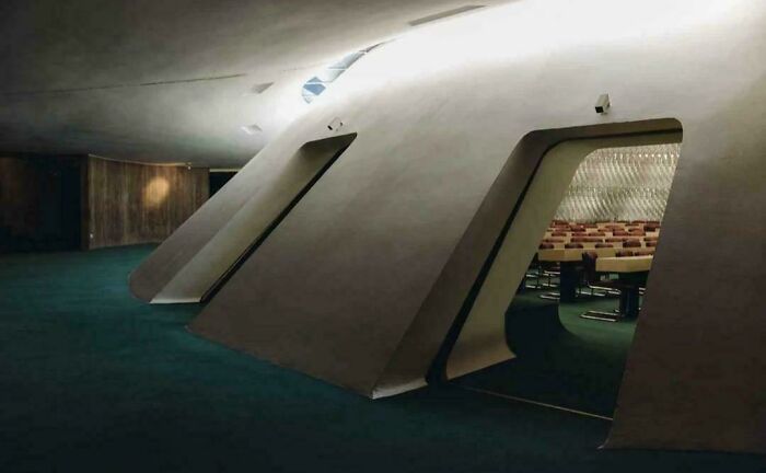 Dark futuristic building interior with angular walls and empty chairs, evoking evil auras like a supervillain headquarters.