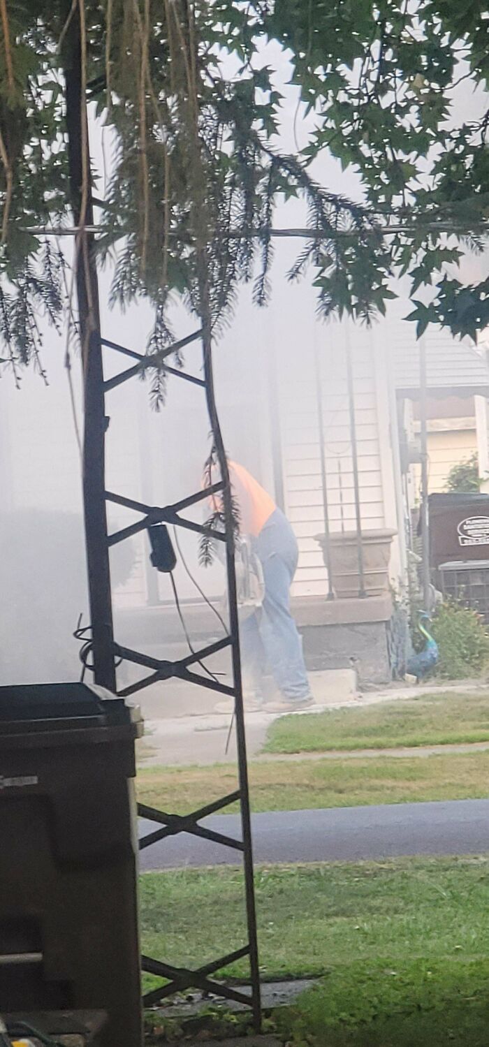 Worker blatantly ignoring safety protocol while using a power tool surrounded by dust and debris outside a residential home.