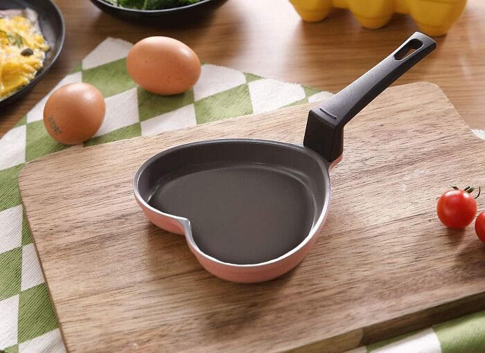 Heart-shaped nonstick pan on a cutting board with eggs and tomatoes, one of the unexpectedly brilliant Amazon finds.