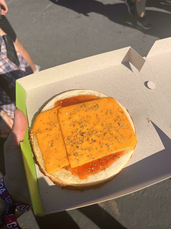 Unusual dish with cheese slices and sauce in a cardboard tray.