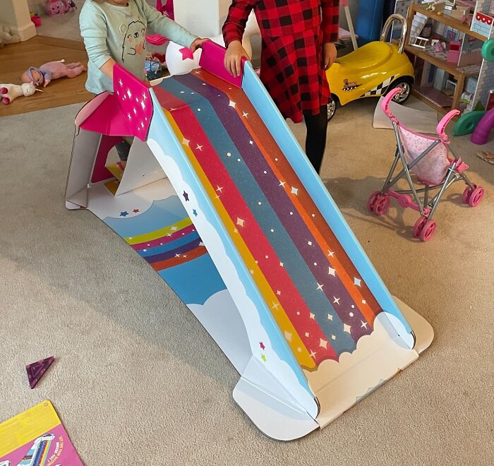 Two kids playing on an indoor colorful rainbow slide, a fun way to keep kids entertained when it's too cold outside.